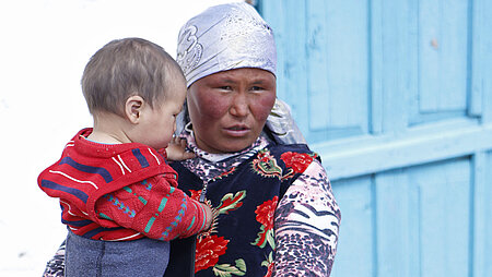 Kirgisische Mutter mit Kind auf dem Arm