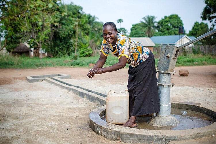 Frau beim Händewaschen an neuem Brunnen