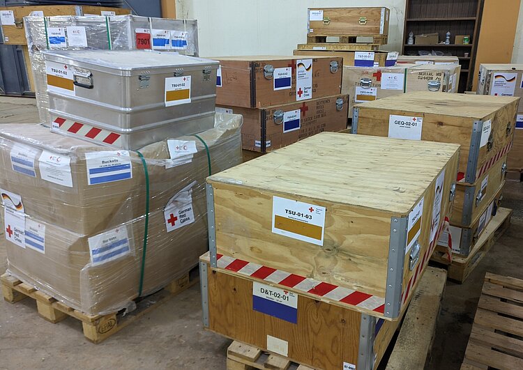 In einem Lagerraum lagern in Kartons verpackte Hilfsgüter des DRK auf Paletten.