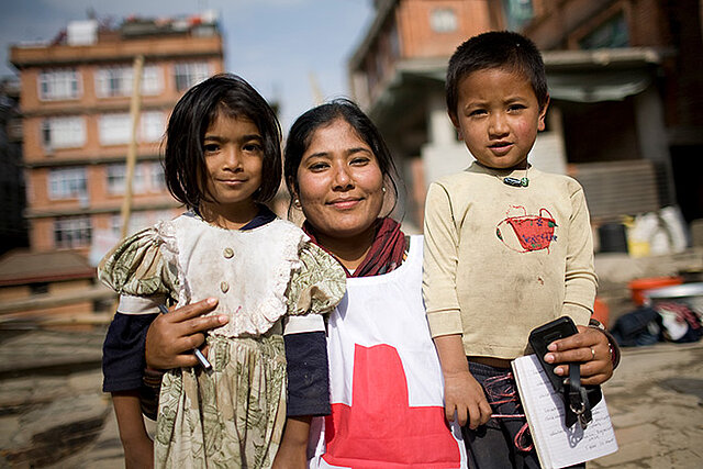 Rotkreuz-Freiwillige mit zwei nepalesischen Kindern