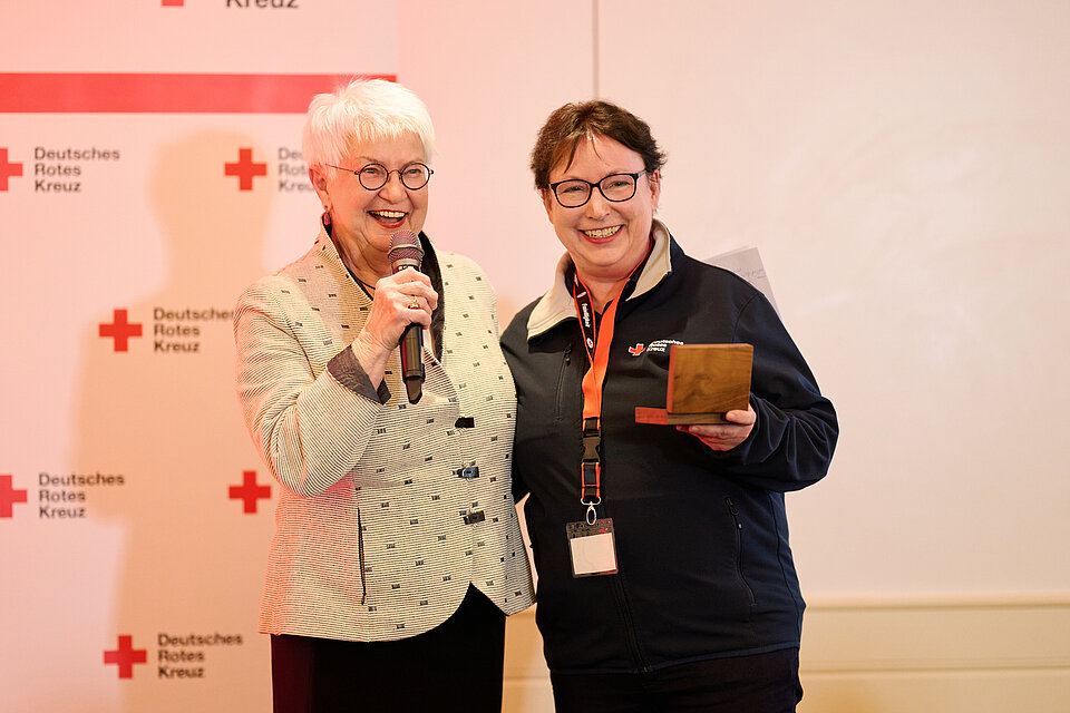 Gerda Hassefeldt steht neben Maike vom DRK KV Nordwestmecklenburg, beide lächeln in die Kamera während der Verleihung der Dankmedaille.