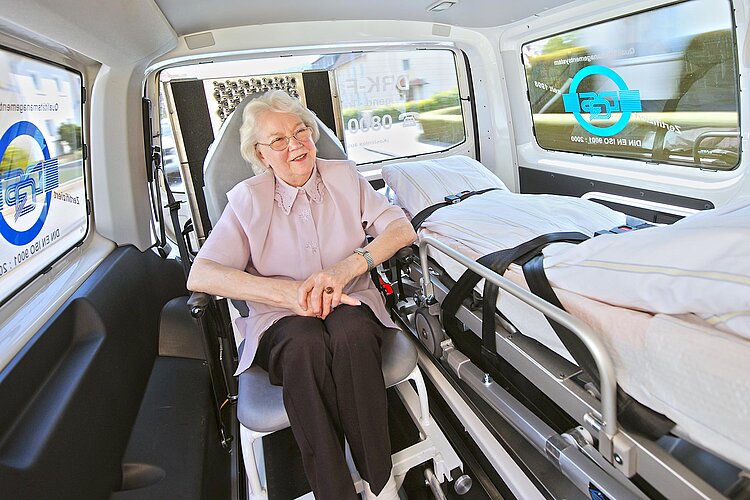 Seniorin auf Transportstuhl in DRK-Fahrdienst-Fahrzeug