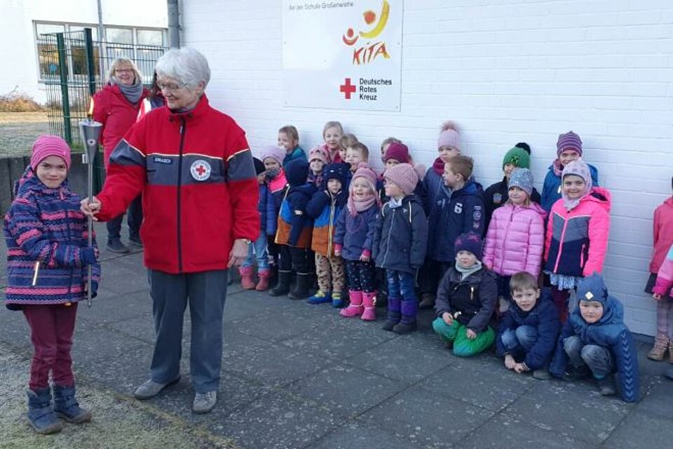 Lena (links) von der DRK Kindertagesstätte an der Schule in Großenwiehe (Kreis Schleswig-Flensburg) das Licht der Hoffnung an Inge Jorasch, stellvertretend für den Kreisverband Nordfriesland