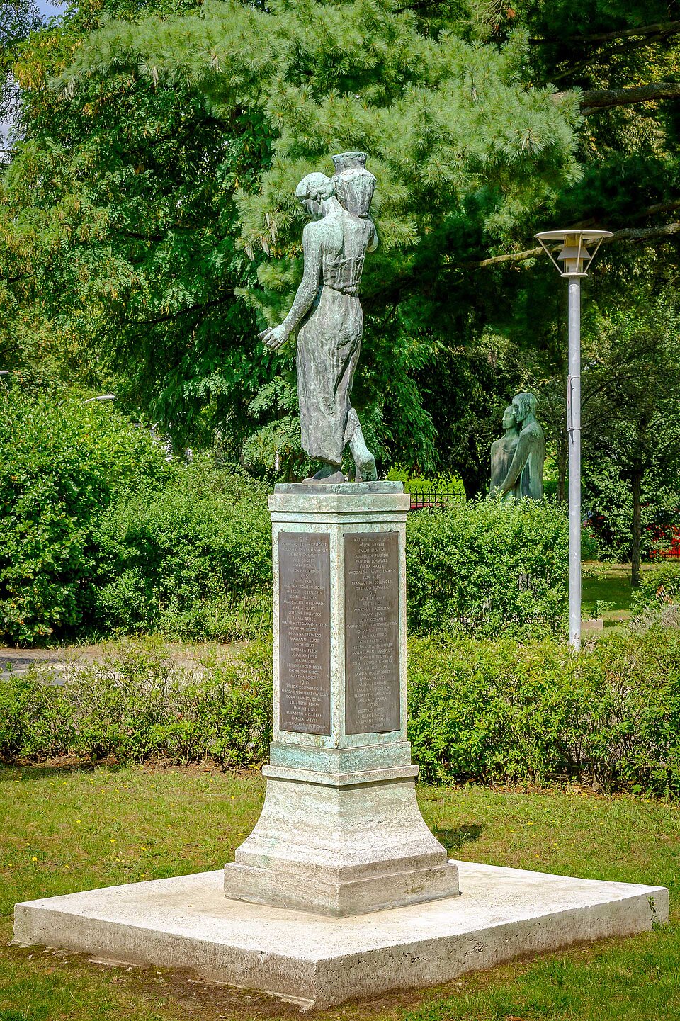 Skulptur ‚Die Wasserträgerin von hinten vor Bäumen