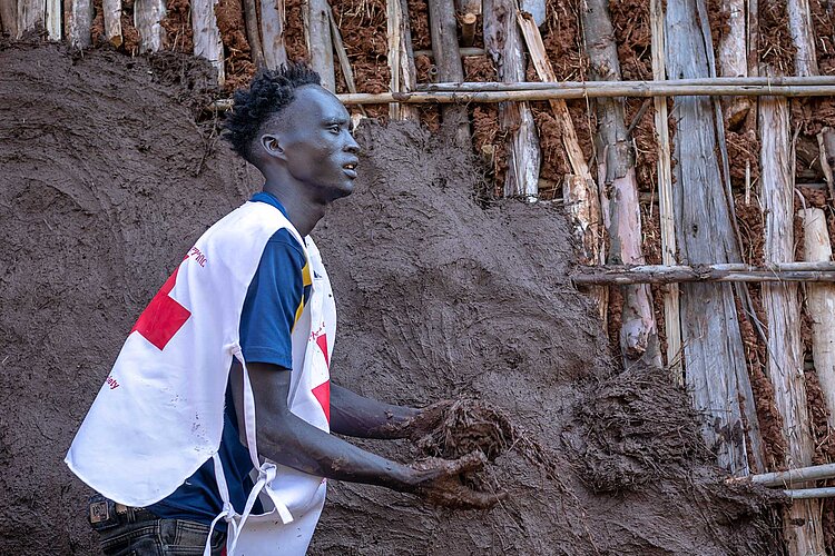 Helfer beim Verkleiden der Außenwände mit Lehmmasse