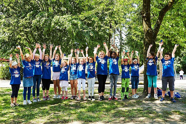 Kinder in blauen T-Shirts strecken Arme hoch