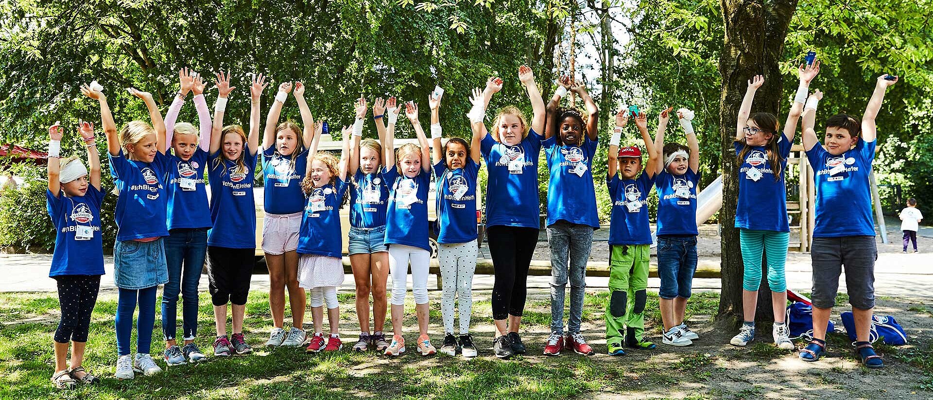 Kinder in blauen T-Shirts strecken Arme hoch