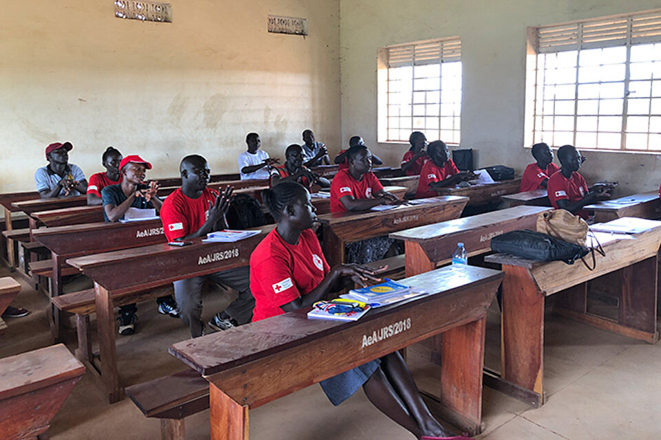 [Translate to Englisch:] Ugandische Rotkreuzler an Schulbänken bei Schulung zu Maßnahmen gegen Hunger