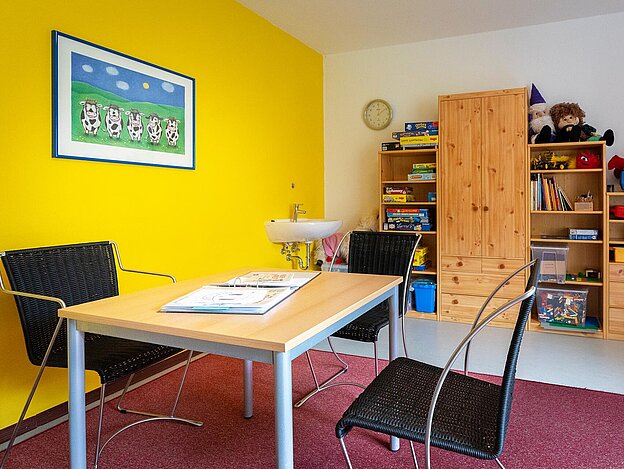 Raum mit Schreibtisch, Schrank und gelber Wand