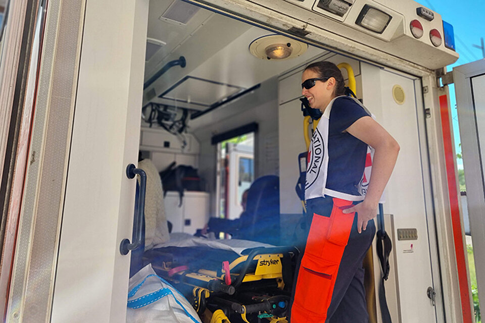 Ein Mitarbeiter des IKRK steht vor einem Rettungstransportwagen und telefoniert.