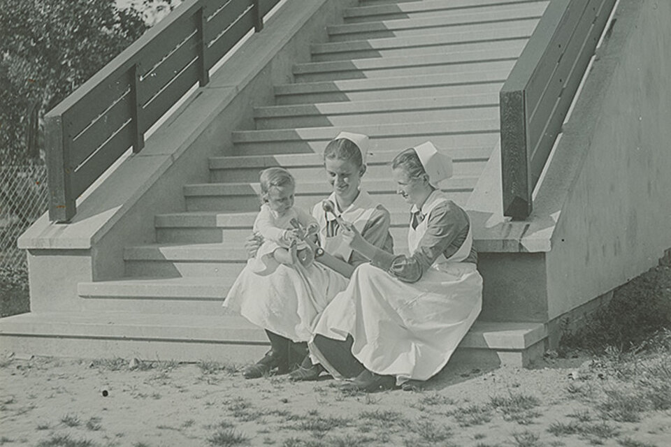 Krankenschwestern mit einem kleinen Kind auf der Treppe zur Kinderklinik