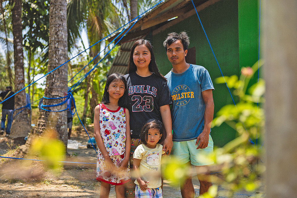 Familie vor gesichertem Haus in Katastrophengebiet auf den Philippinen 