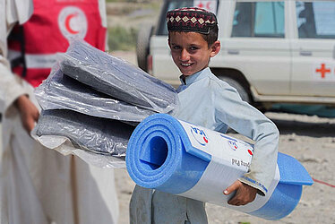 Afghanischer Junge mit Isomatte und Decke