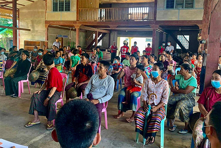 Menschen in Myanmar bei Information vor Hilfsgüterverteilung