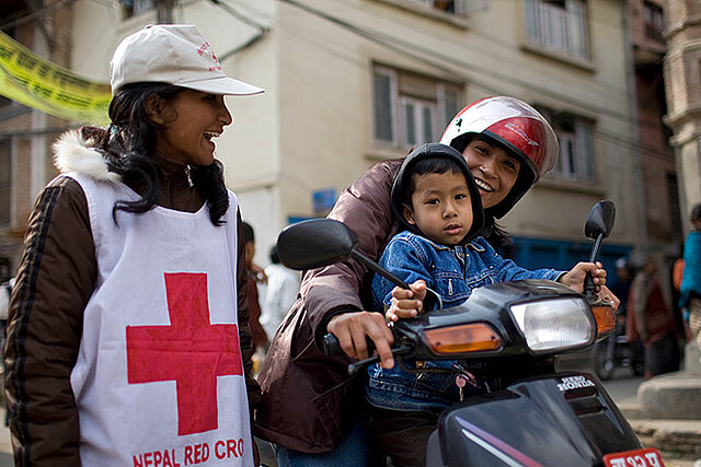 Nepalesische Rotkreuzhelferin im Gespräch mit Mutter auf Moped