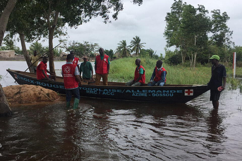 Mitarbeiter des Togolesischen Roten Kreuzes mit einem Boot in einem überfluteten Gebiet 