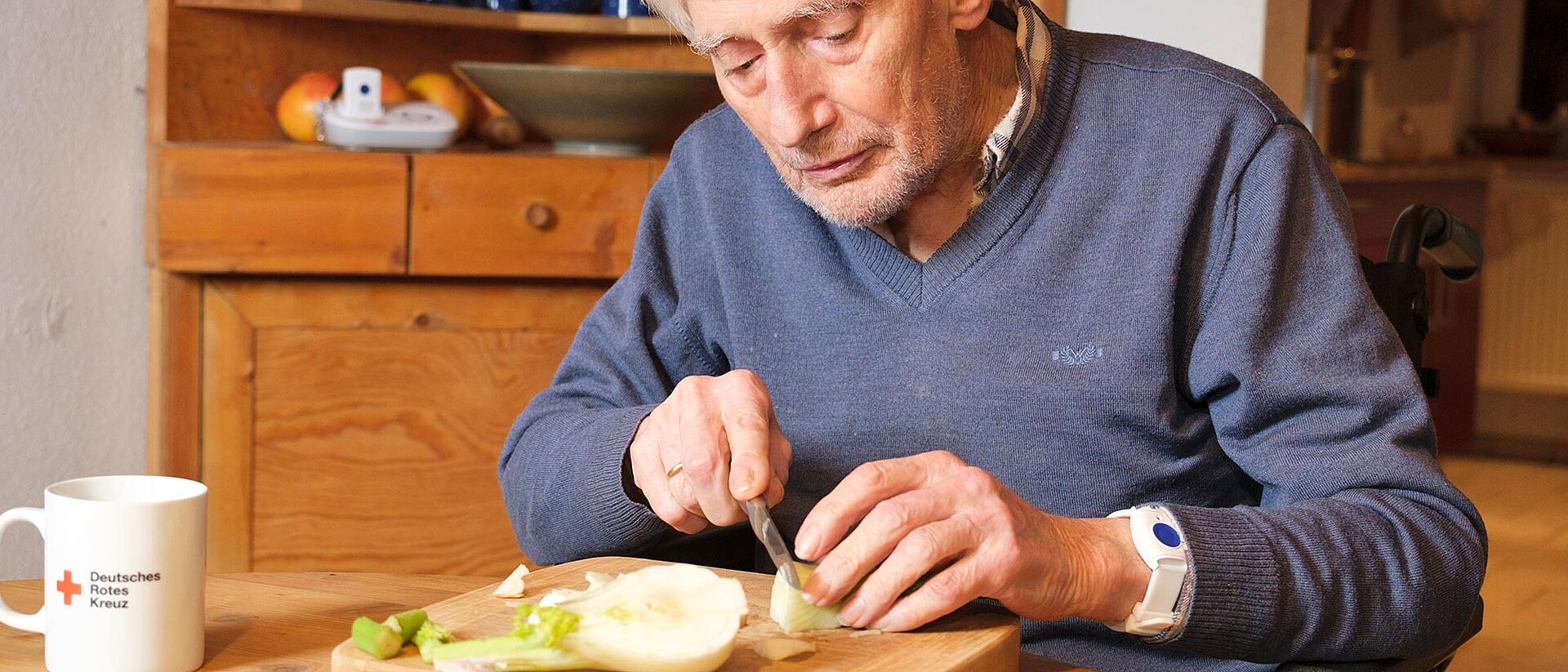 Senior mit Notarmband am Handgelenk schneidet Gemüse