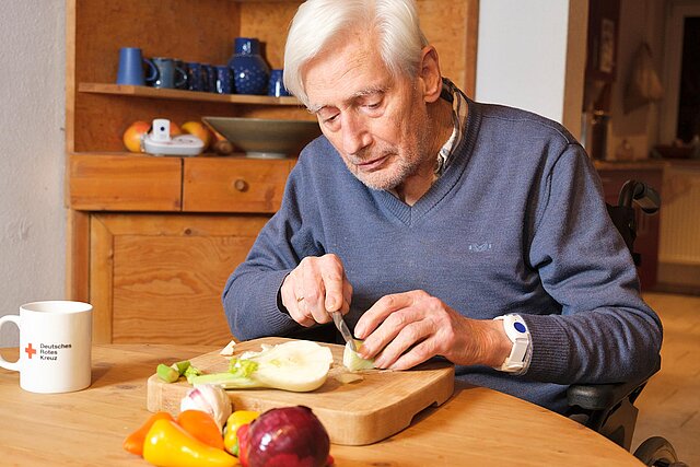 Senior mit Notarmband am Handgelenk schneidet Gemüse