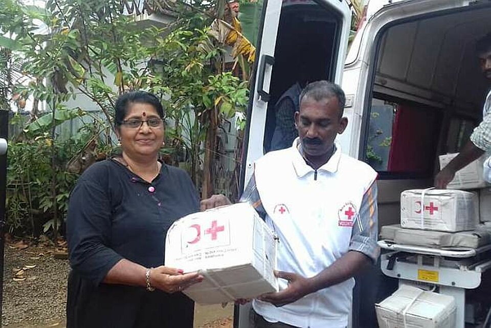 Frau erhält nach Jahrhundertflut in Südindien eine Unterstützung durch das Rote Kreuz.