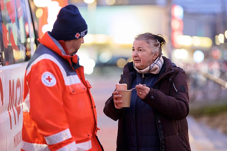 Ehrenamtlicher und obdachlose Frau im Gespräch