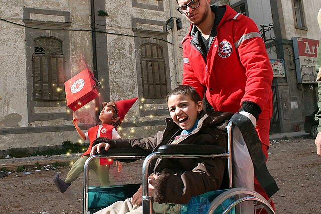 Rotkreuz Helfer schiebt Mädchen im Rollstuhl