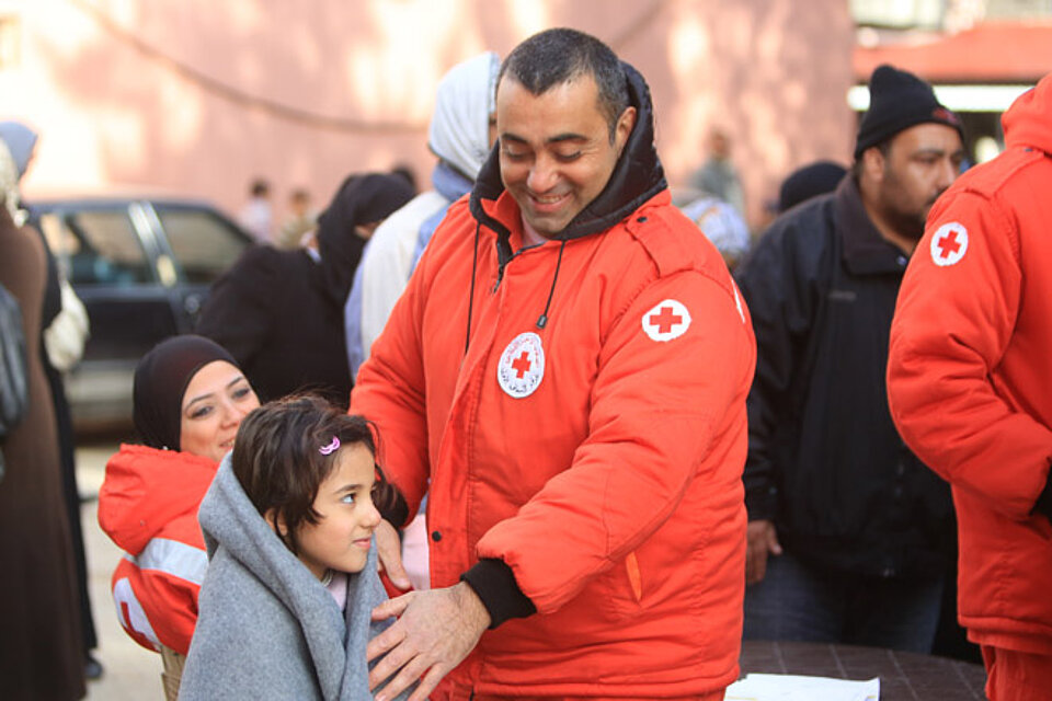 Ein Helfer des Libanesischen Roten Kreuzes mit einem Flüchtlingskind