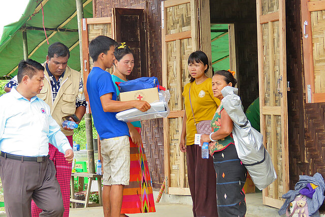 Menschen in Myanmar mit Hilfsgütern im Gespräch