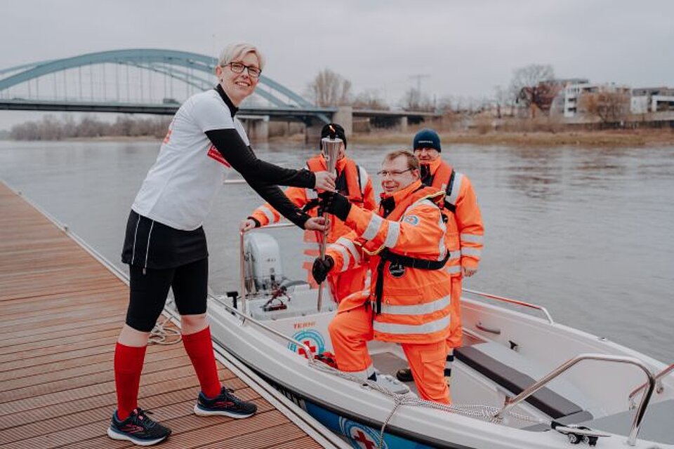 Die DRK-Fackel wird von der Wasserwacht Magdeburg an eine DRK-Ehrenamtliche übergeben