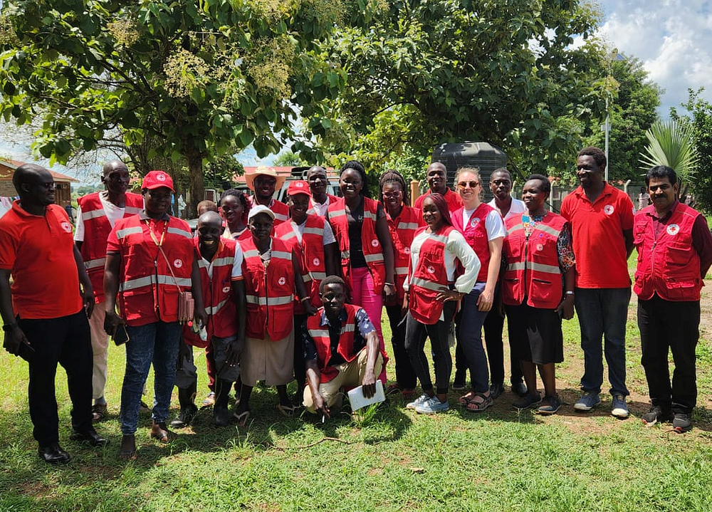 Eine Gruppe mit vielen Menschen in Rotkreuz-Kleidung steht im Freien und lacht in die Kamera