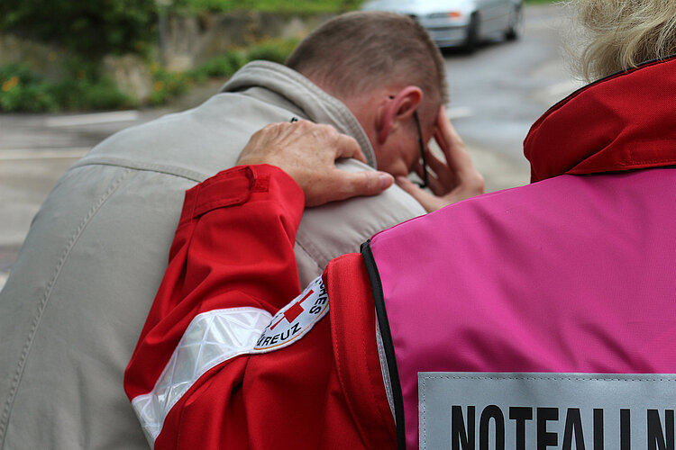 Psychosoziale Notfallversorgung DRKlerin legt Arm auf weinenden Mann