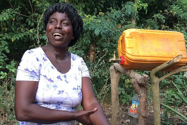 Togolesin neben Handwascheinrichtung aus Wassercontainer
