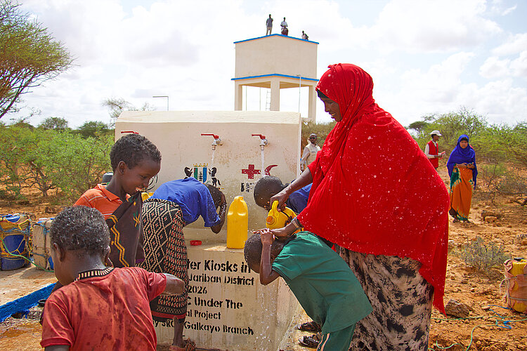 Ein durch das Rote Kreuz errichteter Brunnen in Somalia Frau mit Kindern an einem Brunnen in Somalia