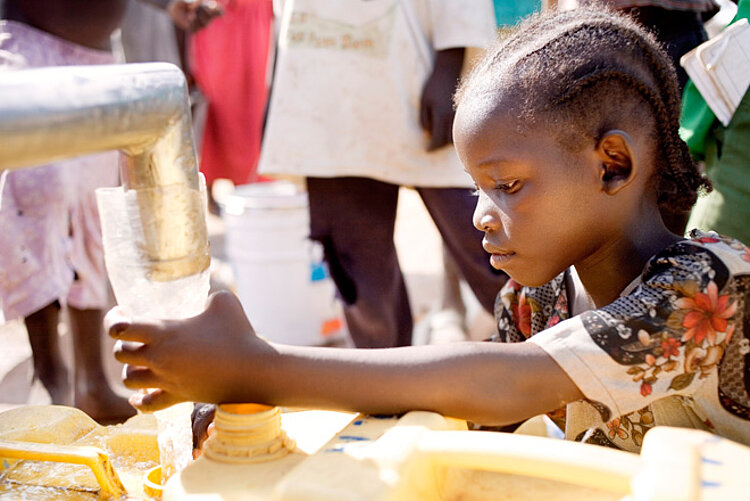 Foto: Ein sudanesisches Mädchen füllt Wasser in einen Kanister