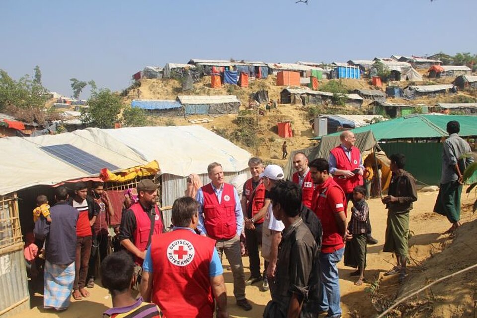 DRKler vor Hütten in Flüchtlingscamp