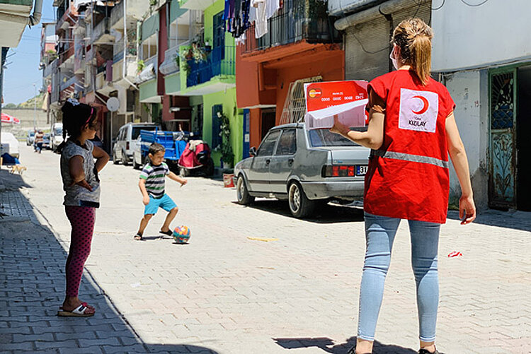 Türkische Rothalbmondmitarbeiterin spielt mit einem Kind Fußball 