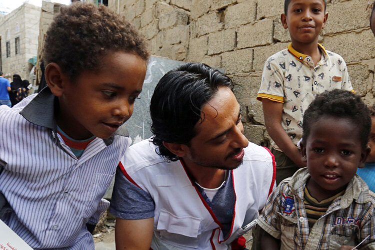 Foto: Rothalbmond-Helfer im Gespräch mit einer Kindergruppe