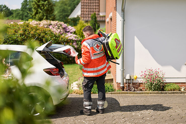 DRKler am Kofferaum eines Einsatzwagens