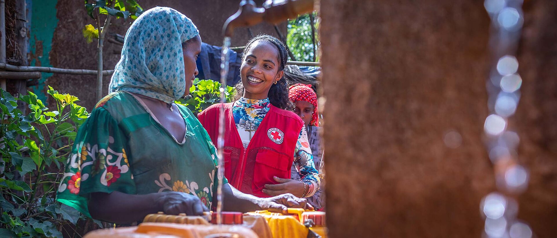 Frau und Helferin sprechen am Brunnen