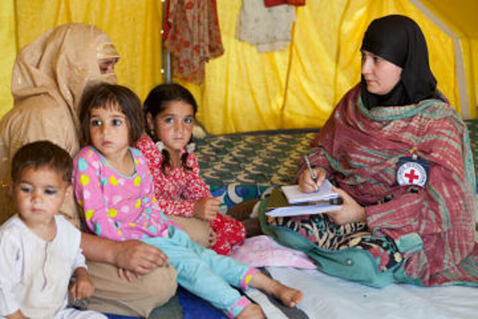 Foto: Eine pakistanische Frau mit ihren Kindern im Gespräch mit einer Rotkreuzhelferin.
