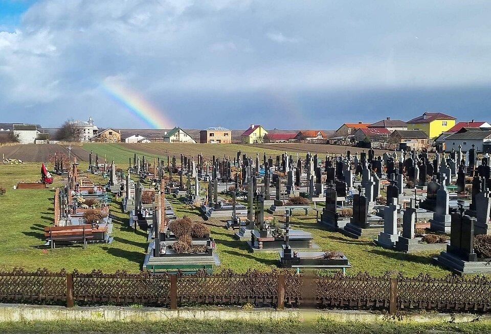 Landschaft mit Friedhof und Regenbogen