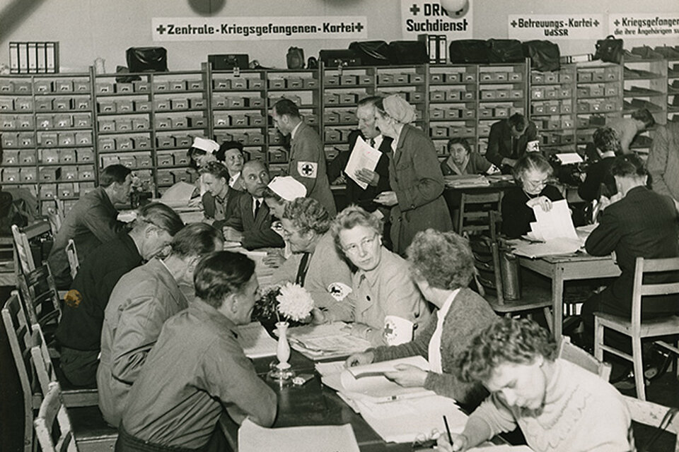 DRK-Mitarbeiter und Hilfesuchende im Saal der Zentralen Kriegsgefangenen-Kartei