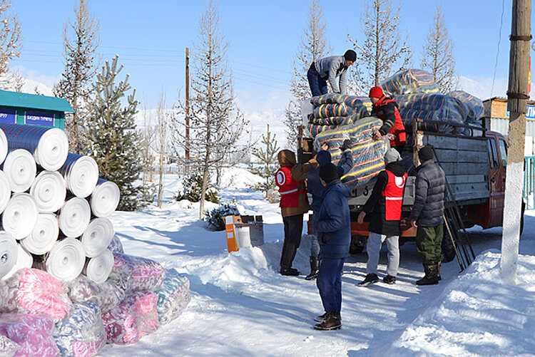 Rothalbmondhelfer laden Winterhilfsgüter von einem Transporter.