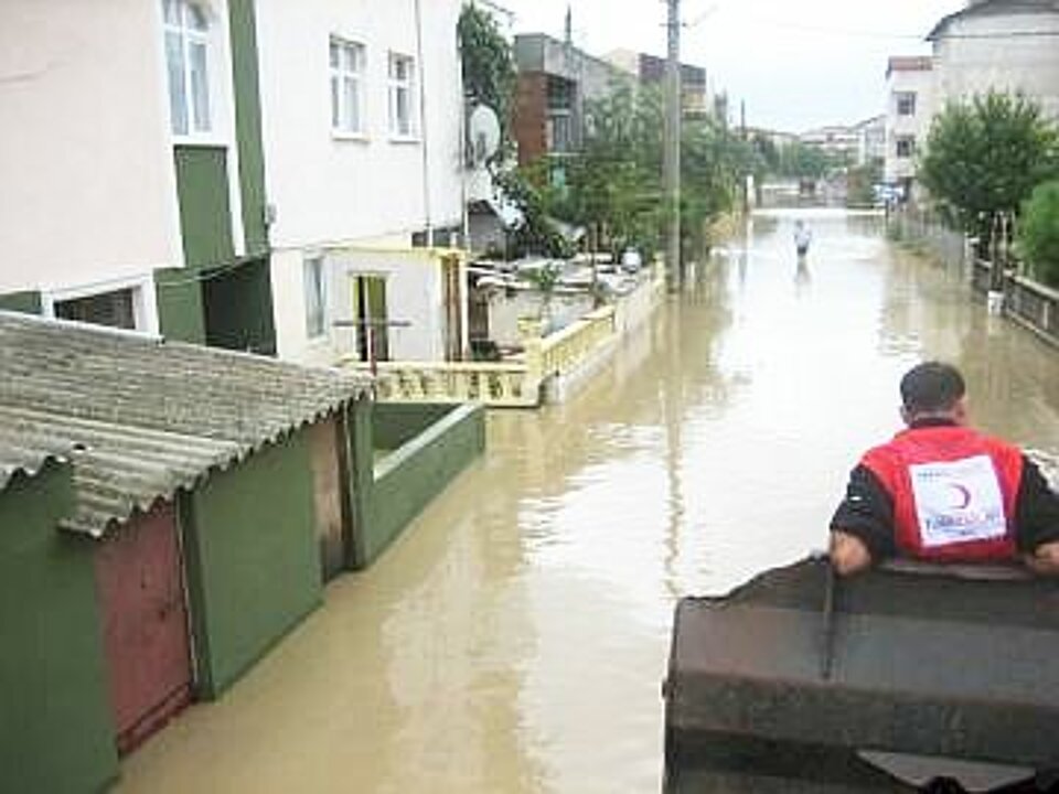 Foto: Ein Helfer des Türkischen Roten Halbmondes mit dem Rücken zum Betrachter auf einem Motorboot, dass durch einen überschwemmten Straßenzug in Istanbul fährt