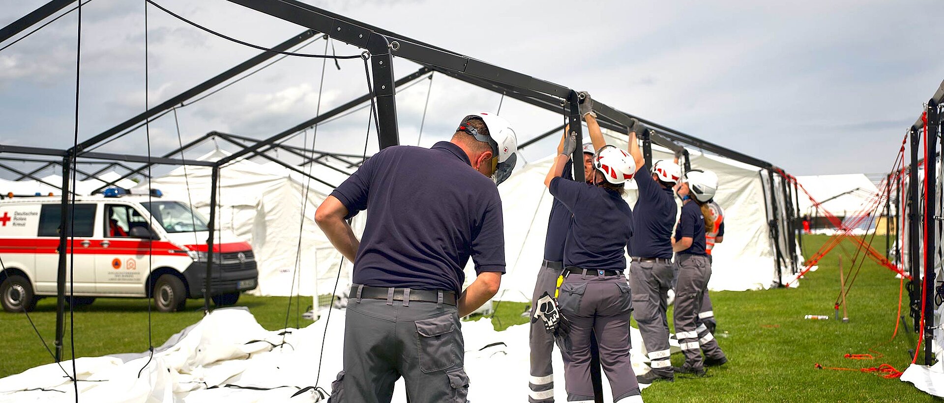 Helfende bauen ein Zelt auf