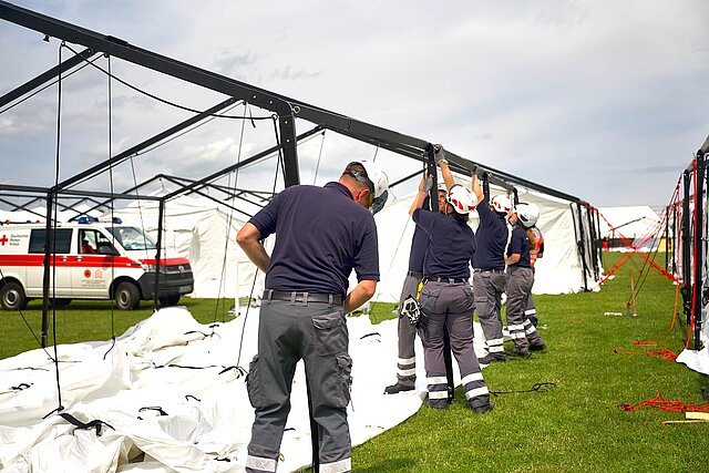 Helfende bauen ein Zelt auf