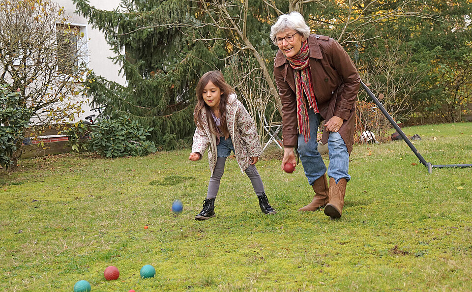 Ein Mädchen und eine Seniorin spielen zusammen auf einer Wiese