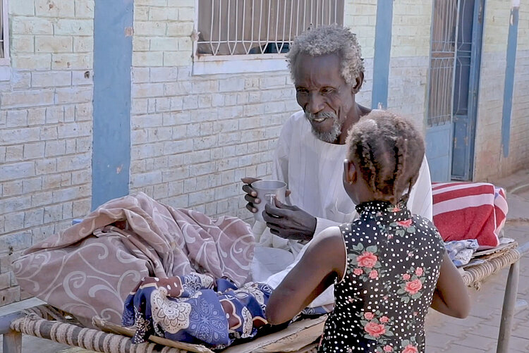 Mann spricht mit einem kleinen Mädchen in einer Klinik, Sudan 