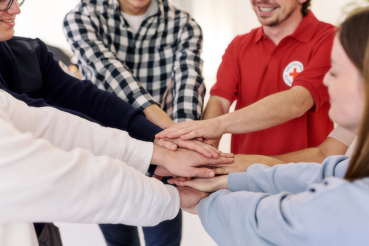 Corporate Volunteering: Mitarbeitende legen Hände übereinander