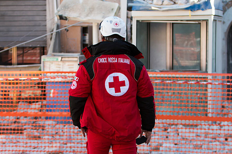 Mitarbeiter des Italienischen roten Kreuzes vor Häusertrümmern
