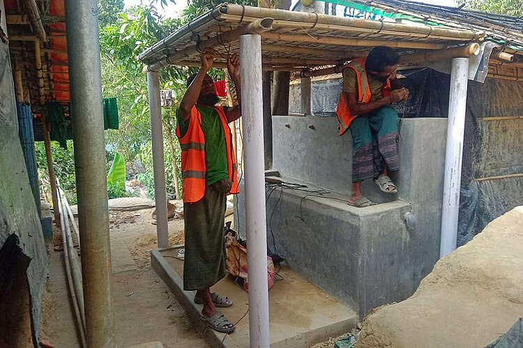 Zwei Helfer errichten Dach über Wasserstelle